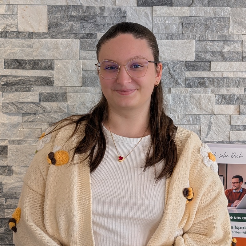 Augenoptikerin mit Brille vor einer Steinwand.